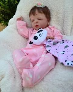Close-up of 19-inch reborn baby doll sleeping in pink heart pajamas with panda plush toy