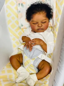 Detailed close-up of a sleeping reborn baby doll with curly hair in a white romper