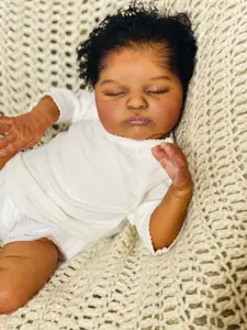 Close-up of deep skin tone reborn doll with black curly hair on a knit blanket