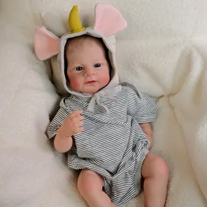 Realistic 18-inch reborn baby doll in striped romper with unicorn hoodie on white rug