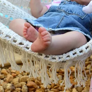 Handgefertigte Makramee-Babyschaukel mit Fransen und Puppe in blauem Jeanskleid