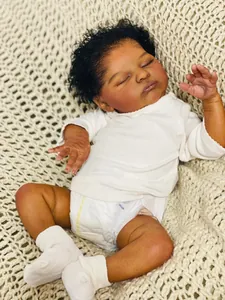 Detail of 19-inch reborn baby doll Laura with dark skin, curly hair and white outfit