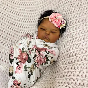 Lifelike 19-inch reborn baby doll with deep skin tone, curly hair, and floral swaddle wrap