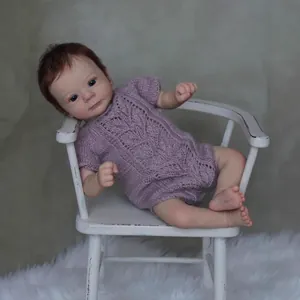 Poupée réaliste Felicia de 18 pouces en tenue de tricot violette sur chaise blanche