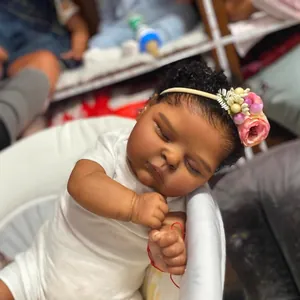 Lifelike 19-inch reborn baby doll with deep skin tone, curly hair, and floral headband
