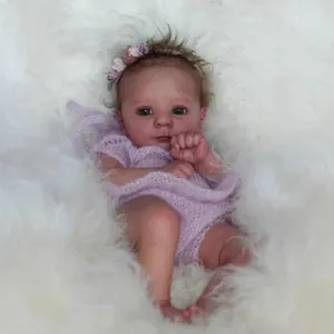 Lifelike 18-inch Reborn baby doll in purple knit romper with floral headband on plush background