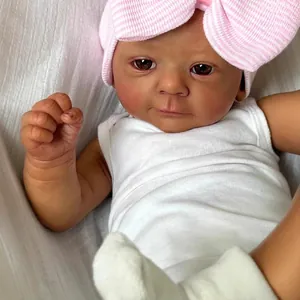 Realistic 18-inch baby doll with deep skin tone wearing a pink bow hat and white outfit