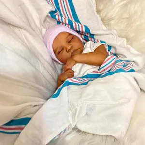 Poupée reborn réaliste de 18 pouces avec bonnet rose dormant sur un tapis de fourrure blanc