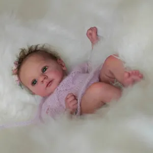 Lifelike 18 inch Reborn baby doll in pink knit outfit on soft white plush background