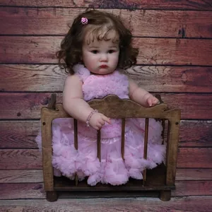 Realistic 24-inch reborn toddler doll with curly brown hair in a pink mesh dress