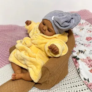 Realistic 19-inch reborn baby doll in yellow bathrobe and grey headwrap on sofa