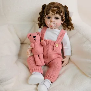 Reborn baby doll Betty with curly hair, pink overalls and small knitted bear toy