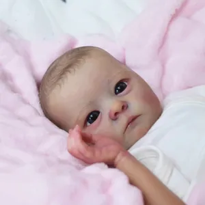 Realistic 16-inch reborn baby doll in white long-sleeve onesie on pink plush rug