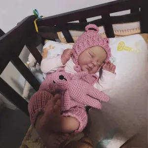 Reborn baby doll Valentina in pink crochet romper and hat sleeping in a wooden crib