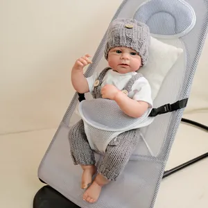 Realistic 19-inch newborn baby doll in gray knitted overalls sitting in a baby rocker