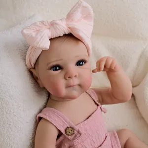 Poupée réaliste de 19 pouces avec bandeau rose et salopette en tricot sur tapis blanc doux