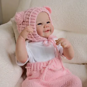 Realistische 19-Zoll-Reborn-Puppe mit rosa Bärenmütze und Strick-Latzhose auf Plüschsitz