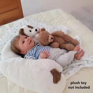 19-inch reborn baby doll in blue striped outfit resting on a white plush u-shaped pillow