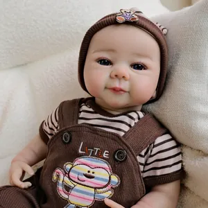 Handmade 19-inch reborn baby doll in brown monkey overalls and knit hat on white soft plush