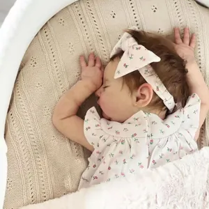 Realistic 19-inch reborn doll wearing a pink floral romper and matching headband