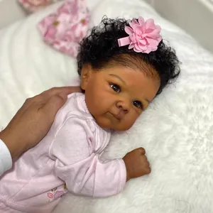Muñeca bebé realista de 18 pulgadas con piel oscura y traje rosa sobre felpa blanca suave
