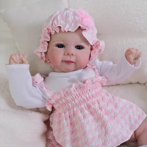Realistic 19-inch baby doll in pink houndstress dress with matching sun hat on plush blanket