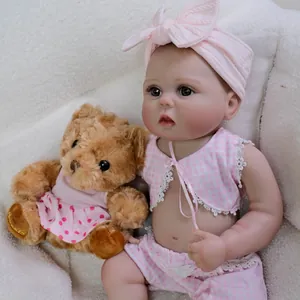 Lifelike 22-inch reborn baby doll in pink checkered lace outfit with a small plush teddy bear