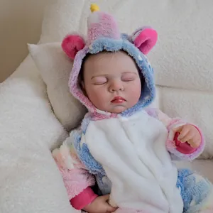 Reborn baby doll Charlotte sleeping in a plush unicorn onesie on a white sofa