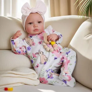 Lifelike 19-inch newborn baby doll in floral romper with pink bow and wooden rattle