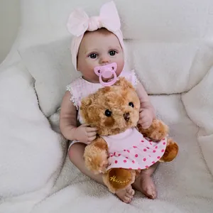 Realistic 22-inch reborn baby doll in pink checkered dress with plush bear and pacifier
