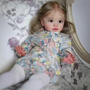 Lifelike 26-inch reborn baby doll in floral romper sitting on a vintage armchair