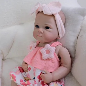 18-inch lifelike reborn baby doll in pink floral dress and headband on soft chair