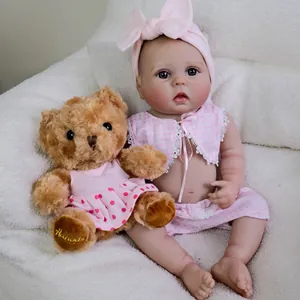 Realistic 22-inch reborn baby doll in pink checkered vest with plush teddy bear prop