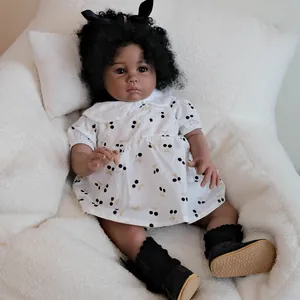 Lifelike black reborn baby doll with curly hair wearing a white cherry print dress