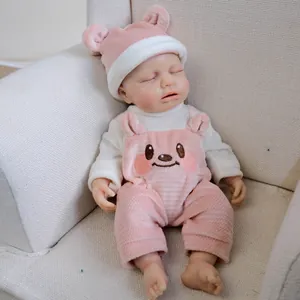 Bambola realistica da 12 pollici che dorme con vestito da orso rosa su un divano morbido