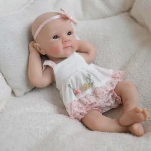 Realistic 8-inch silicone reborn baby doll wearing a pink floral outfit on white plush blanket