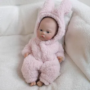 12-inch realistic baby doll wearing pink plush bunny onesie on soft white background
