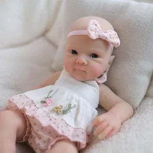 Realistic 8-inch silicone baby doll in white floral dress on soft white plush