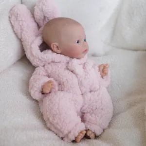 Realistic 12 inch Meadow reborn doll wearing a soft pink plush bunny romper on white blanket