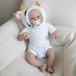 Realistic 19-inch reborn baby doll wearing a cow hat and white onesie on soft chair