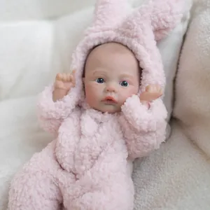 12-inch realistic baby doll wearing a pink fleece bunny jumpsuit with blue eyes