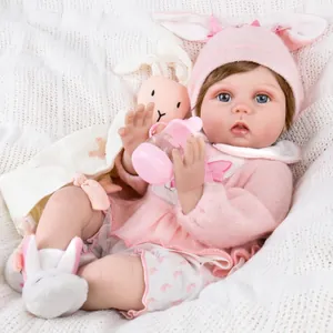 Poupée reborn réaliste de 55cm avec tenue lapin rose et biberon sur couverture