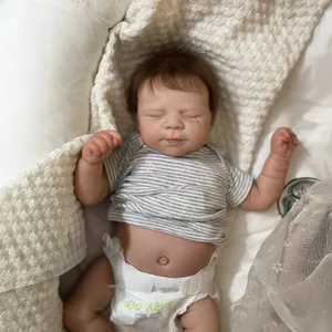 Lifelike 19-inch reborn baby doll with striped shirt and knitted blanket in a cozy setting