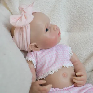 Lifelike 18 inch solid silicone baby doll in pink checkered outfit on white plush mat