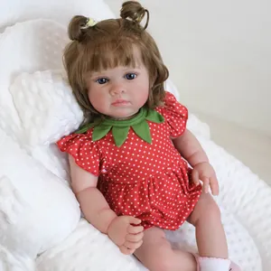 Reborn-Babypuppe in rotem Erdbeerkleid mit braunen Locken auf weicher Matte