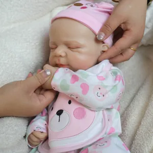 Realistic 18-inch soft silicone sleeping baby doll in pink bear outfit on plush mat