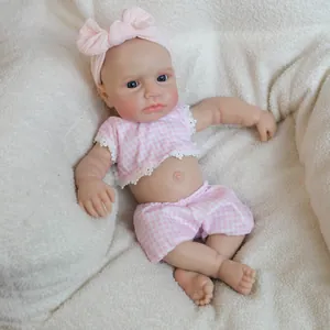 Realistic 18-inch solid silicone baby doll wearing a pink plaid outfit on a soft white blanket