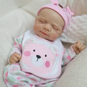 Realistic 18-inch solid silicone baby doll in pink bear outfit on a white blanket