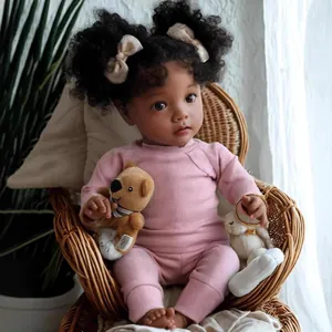 Bambola reborn da 22 pollici con tratti africani in abito rosa e peluche su una sedia