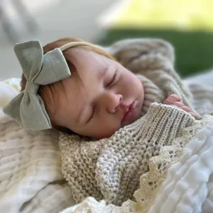 Bambola reborn dormiente da 19 pollici in maglione beige con fascia con fiocco verde